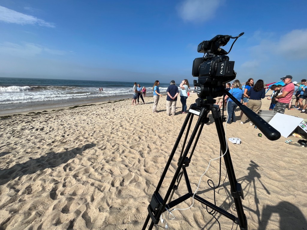 A camera stands on the beach